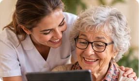 Une soignante aide une résidente à utiliser une tablette